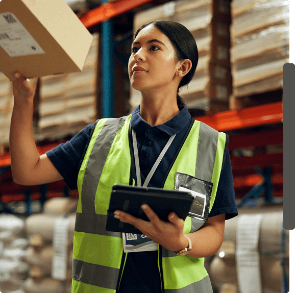 Warehouse worker holding package and tablet.