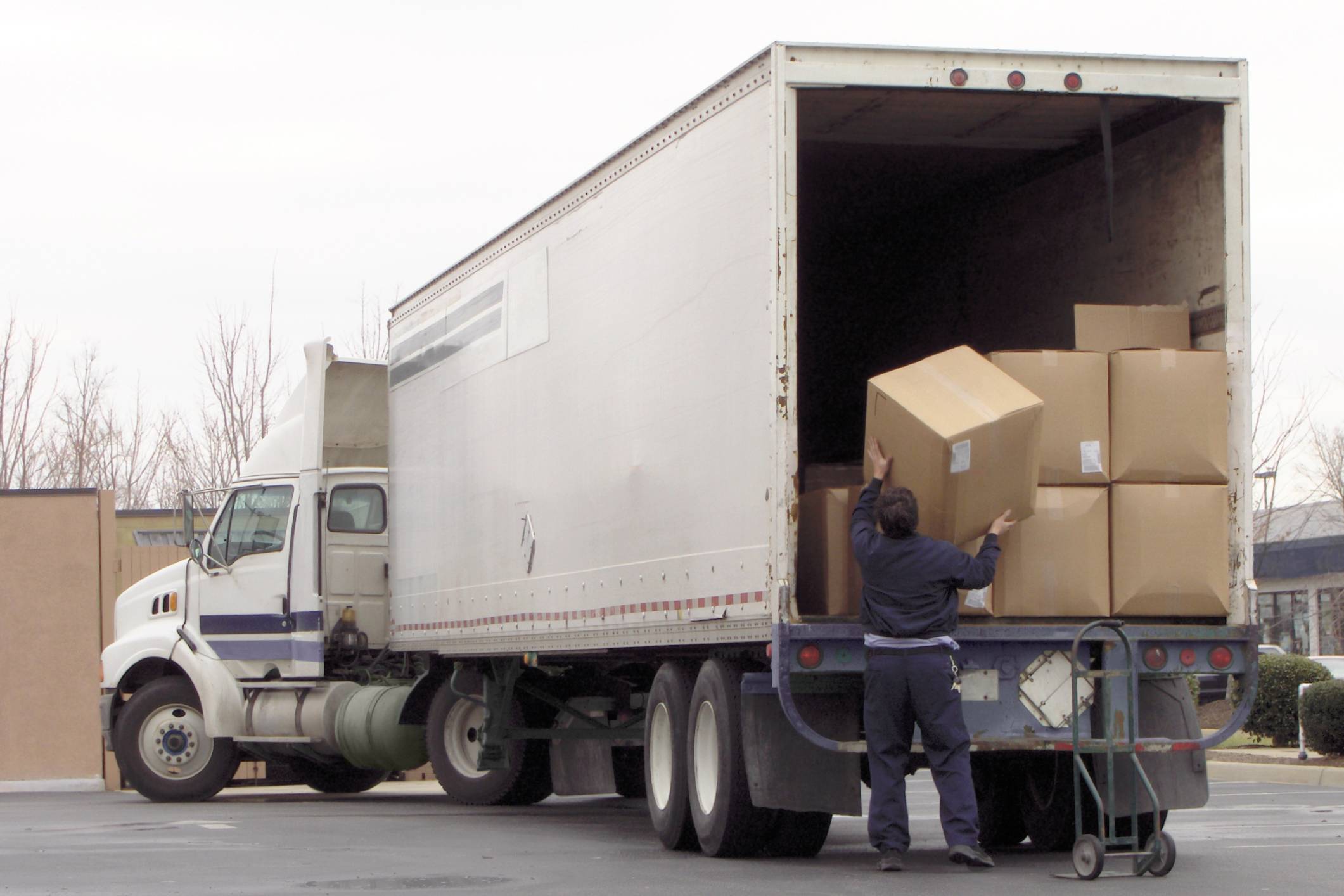 Worker loading boxes onto delivery truck.